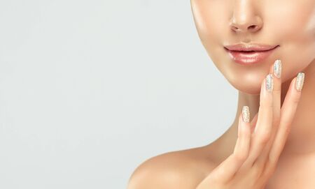 Close-up detail of woman face in a soft make up. Long, graceful fingers in touching tender, silky skin of the face. Cosmetology, face care and make up.の写真素材