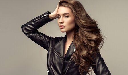 Portrait of attractive woman with long, dense, well groomed hair, dressed in trendy leather jacket. Hairdressing and modern trends.の写真素材