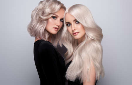 Two examples of blond hairstyle on the heads of nicely looking women. Double portrait of blondes with different length of hair. Beauty, elegance, art of hairstyling.の写真素材