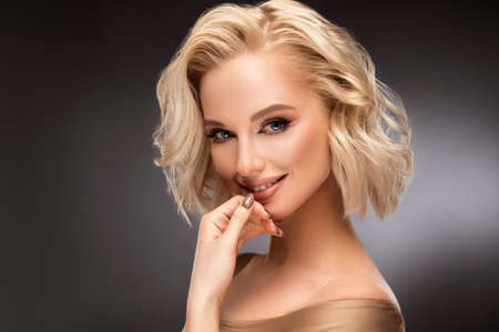 Beautiful looking young blonde woman with the middle length hair, wearing in a delicate makeup. Elegance and hairstyling.の写真素材
