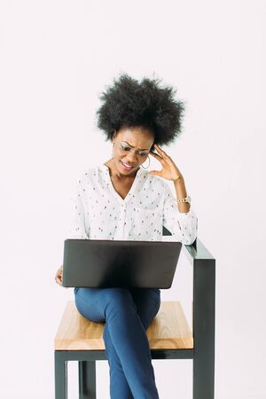 cheerful young afro american business woman concentrated and confused, using laptop, isolated on whiteの写真素材