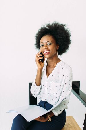 Young smiling african american business woman using the phone, isolated on whiteの写真素材