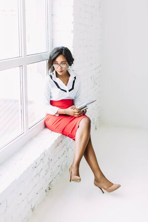 African-American business woman. Beautiful young african woman teacher sitting near the windowの写真素材