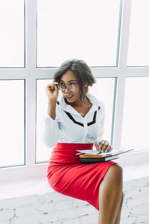 African-American business woman. Beautiful young african woman teacher sitting near the windowの写真素材