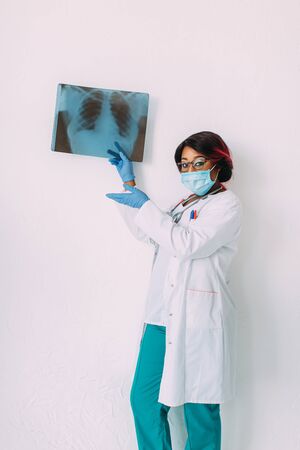 Young smiling African American doctor in medical mask holding patients x-rayの写真素材