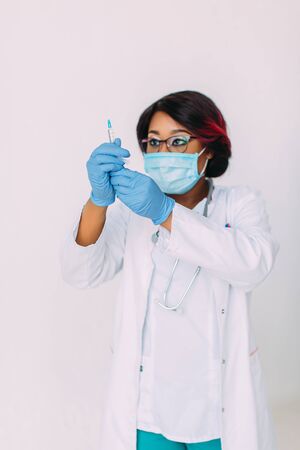 Young smiling African American doctor in medical mask holding a syringeの写真素材