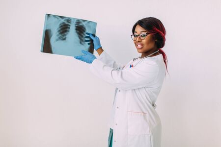 Young African American woman doctor in medical wear looking at x-ray imageの写真素材