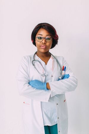 Young smiling African American woman doctor in medical gloves and clothes, isolated on whiteの写真素材