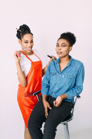 Young beautiful African American woman applying professional make-up by African make-up artist. Studio shootの写真素材