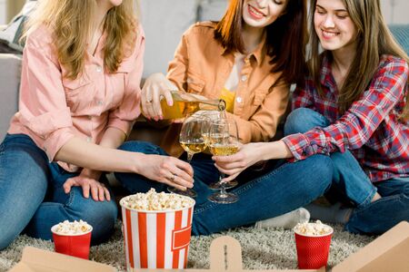young Caucasian women sitting indoor, eating pizza and popcorn and drinking together â friendship, cheerful, celebrationの写真素材