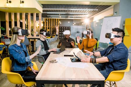 Young happy friends testing video games wearing virtual reality glasses indoors - Cheerful people having fun with new trends technology - Gaming concept.の写真素材