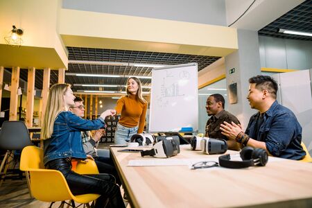 Business team in casual wear having meeting about new project of virtual reality simulator. Young woman in casual wear shaking hands with colleagues in the modern loft officeの写真素材