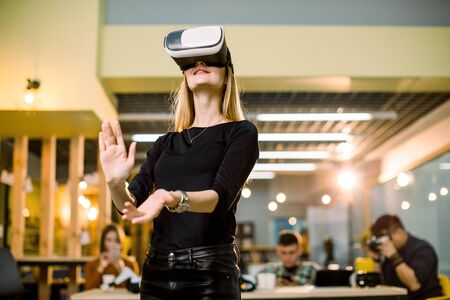 Young Woman Wear Virtual Reality Digital Glasses. Team of young people testing vr goggles on the backgroundの写真素材