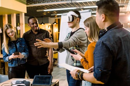 Business team of young multiethnical people presenting new project to a client on a virtual reality simulator. Young Caucasian man the client with VR glassesの写真素材