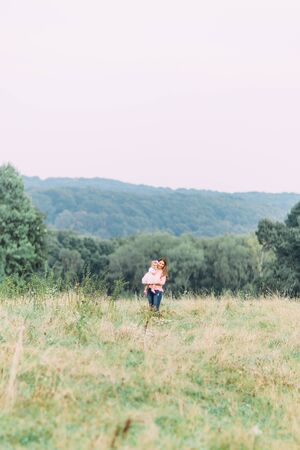 Mother and little daughter playing together in a park. Happy cheerful family. Mother and baby kissing, laughing and hugging in nature outdoorsの写真素材