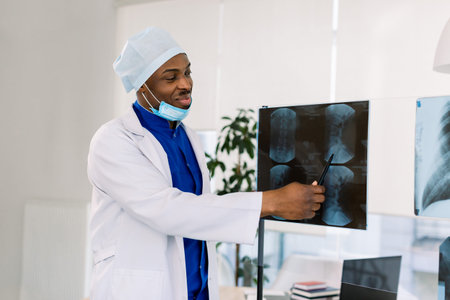 Portrait of young African male doctor surgeon or radiologist looking at a radiographyの写真素材