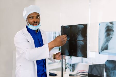 Portrait of young African male doctor surgeon or radiologist looking at a radiographyの写真素材