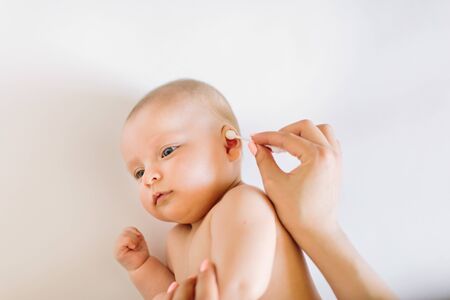Mother hand cleaning baby ear with cotton swabの写真素材