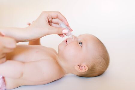 Mother dripping nasal drops for her infant. Baby healthcare conceptの写真素材