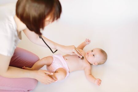 Doctor using a stethoscope to listen to baby's chest checking heart beatの写真素材