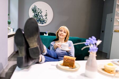 Young pretty smiling Caucasian woman in coffee shop cafe, desserts and coffee on the tableの写真素材