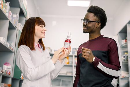 Woman druggist is recommending medicine for young African man client in pharmacy.の写真素材