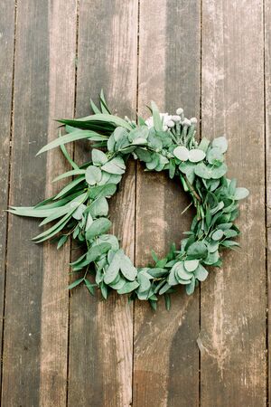 Hands making wedding wreath from eucalypthus and flowers on wooden background. Wedding, rustic eco decorの写真素材
