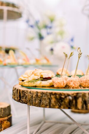 Catering service. Restaurant table with food at event. Round wooden stand with delicious snacksの写真素材