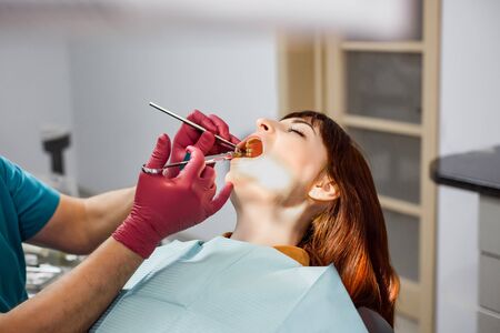Close up of a man dentist in red medical gloves giving his young patient an anesthesia injection in dental clinicの写真素材