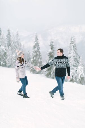 happy loving couple walking in snowy winter forest, spending christmas vacation together. Outdoor seasonal activities. Lifestyle captureの写真素材