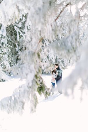 christmas happy couple in love embrace in snowy winter cold forest, copy space, new year party celebration, holiday and vacation, travel, love and relations.の写真素材