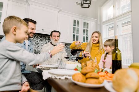family having holiday dinner. Pretty young mother pouring cherry juice for her daughter at holiday dinner. thanksgiving day conceptの写真素材