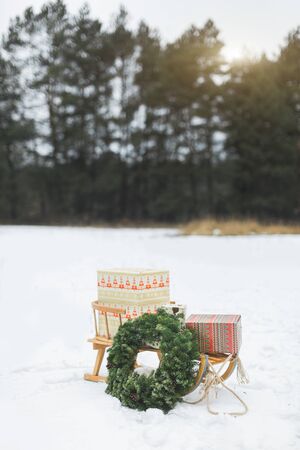 Beatiful wooden Santa's sledge with Christmas gifts and wreath on the snow, over the background of frosty winter forest. Merry Christmas and Happy New Year Conceptの写真素材