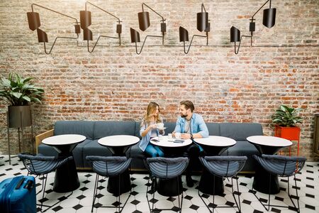 Couple enjoying coffe time sitting at the table in hotel, waiting for check-in for arrival.の写真素材