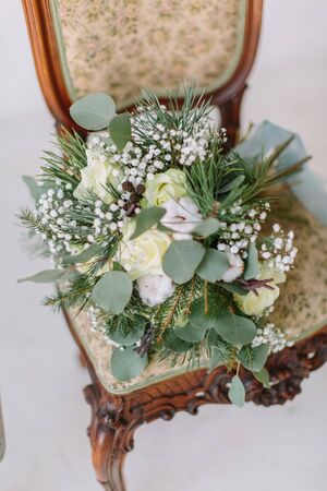 Beautiful wedding bouquet with white roses, pine and eucalyptus lying on the vintage chairの写真素材