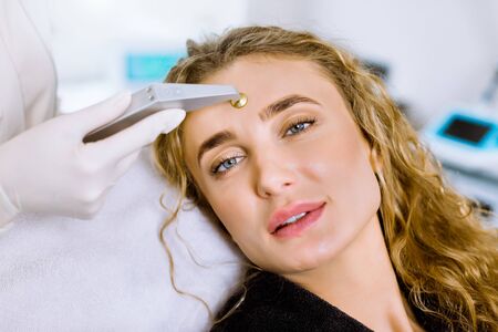Hardware cosmetology. Closeup portrait of face of beautiful young blond woman getting microdermabrasion procedure in a beauty salon or clinic.の写真素材