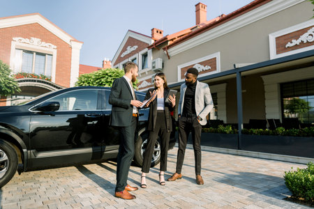 Young Caucasian man car salesman working with clients, business couple African man and Caucasian...