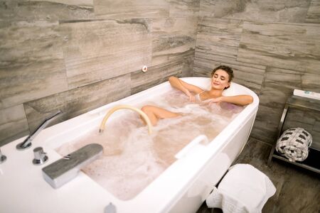 Healthy Spa. Young Caucasian Beautiful Relaxing Woman Lying in the Bath with Hydro Massageの写真素材