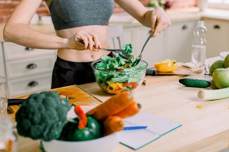 Woman cooking in new kitchen making healthy food with vegetables. Young Caucasian woman in her twenties.の写真素材
