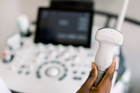 Close up photo of ultrasound scanner in the hands of female African American doctor. Diagnostics....