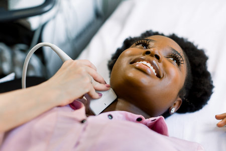 Close up shot of a young smiling African American woman getting her neck and thyroid gland examined...