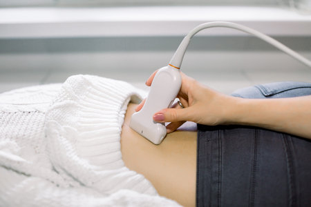 Close up photo of lower back of young woman getting ultrasound test in clinic. Hand of a doctor...