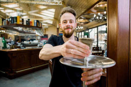 handsome young smiling barmen is preparing a device for smoking, hookah. close up photo.