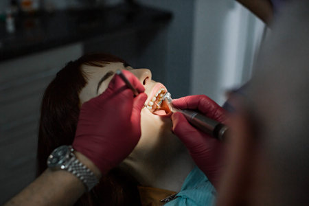 Top agle view of the face of young woman having tooth operation in modern stomatology clinic. Senior...