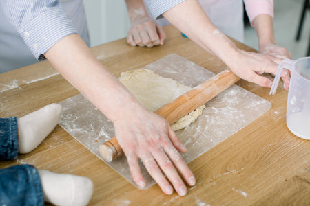 Sheeting dough. Women's hands are holding rolling pin and floured. Hands baking dough with rolling...