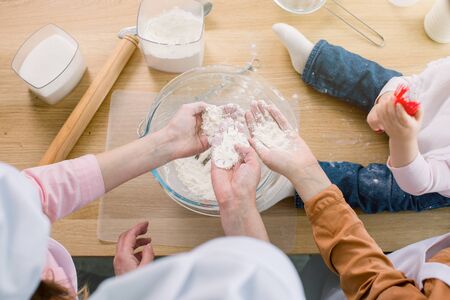 Grandma and her daughters keep flour in their hands, prepare a dough in their kitchenの写真素材
