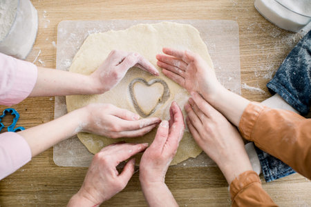 cooking and home concept - close up of female hands making cookies from fresh dough at home. Hands...