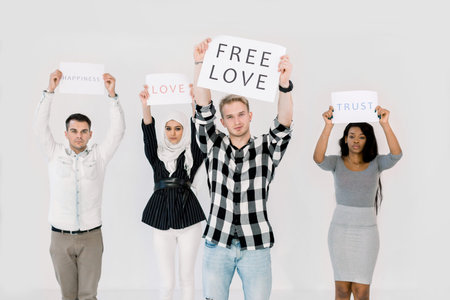 Multiethnica group of young protesters holding posters, protecting LGBT rights, free love, standing on white background. Young Caucasian man with poster stands in front of his friendsの写真素材