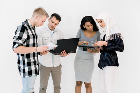 Group Of Four Multi Ethnic Students, working studying together, using laptop and tablet, standing On...