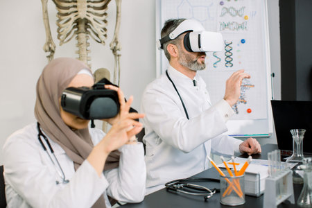 Group of two creative doctors researchers, Muslim woman in hijab and mature Caucasian man, doing...